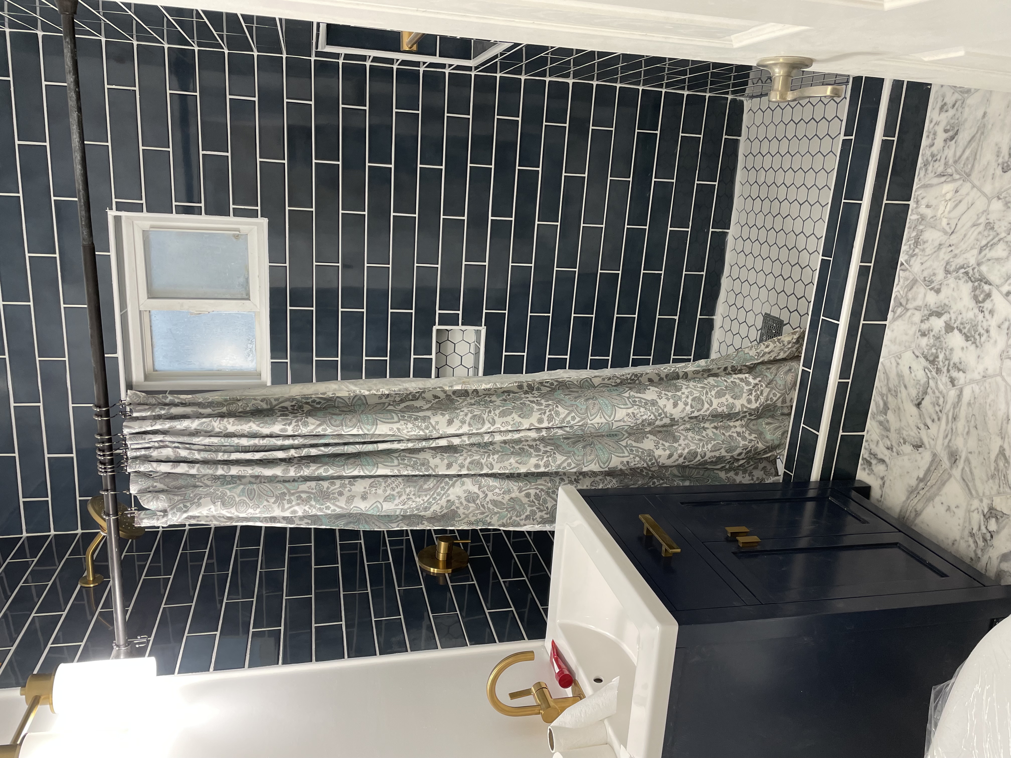 Luxury bathroom renovation with navy tile walls, gold fixtures, and custom vanity in Coronado